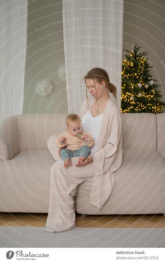Mutter und Baby genießen eine gemütliche Zeit zu Hause heimwärts Liege Weihnachtsbaum Angebot Moment Frau Kind Sitzen im Innenbereich warm Licht festlich Saison