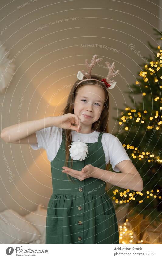 Junges Mädchen feiert Weihnachten mit festlichem Stirnband Rentier Liebe gestikulieren Baum Lichter glühend Feier Freude jung Kind Feiertag Saison