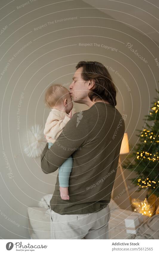 Zärtlicher Moment zwischen Vater und Kind zu Weihnachten Mann Baby Kuss Weihnachtsbaum Zärtlichkeit festlich Atmosphäre Vaterschaft Bonden Liebe Pflege