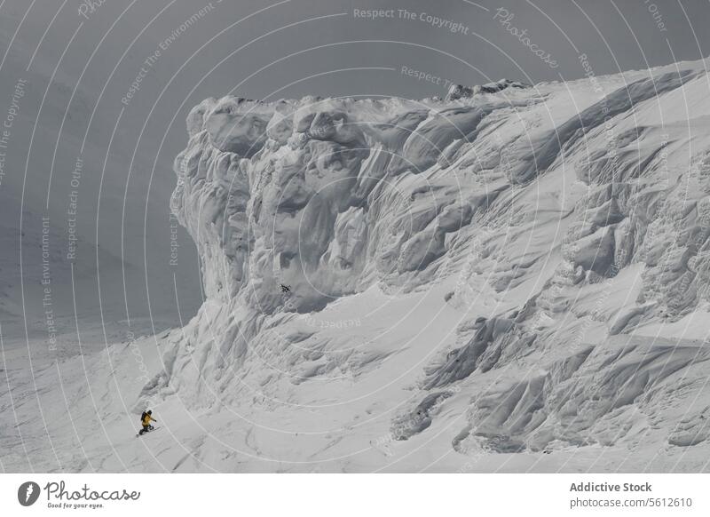 Rückenansicht von unerkennbaren Abenteurer Snowboarder mit Rucksack Snowboarden auf Schnee bedeckt majestätischen Berg während sonnigen Tag im Winterurlaub