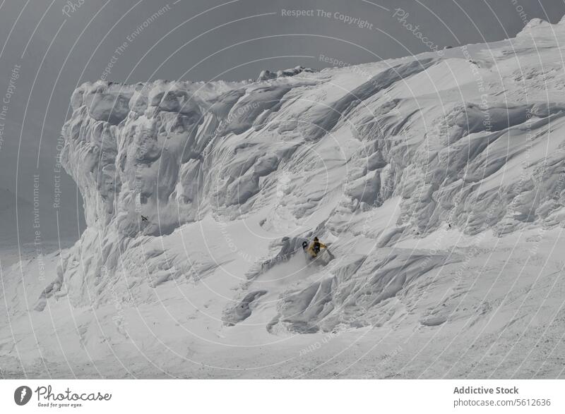 Rückenansicht von unerkennbaren Abenteurer Snowboarder mit Rucksack Snowboarden auf Schnee bedeckt majestätischen Berg während sonnigen Tag im Winterurlaub