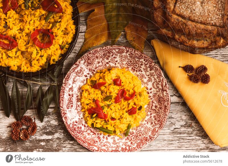 Traditionelles Reisgericht, serviert mit Käse und rustikalem Brot Speise Paella Tisch Holz Scheibe Keil Mahlzeit farbenfroh Garnierung Gemüse Präsentation