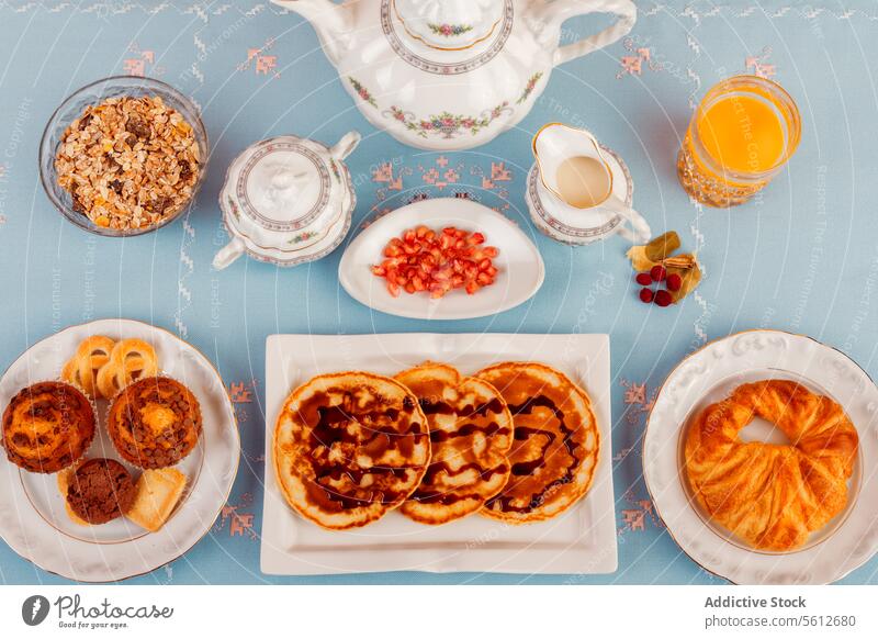 Gesundes Frühstück auf einem blauen Tisch Gesundheit Orangensaft Tee Müsli melken Teekanne Tasse Frucht Muttern Brötchen Gebäck Teller Schalen & Schüsseln