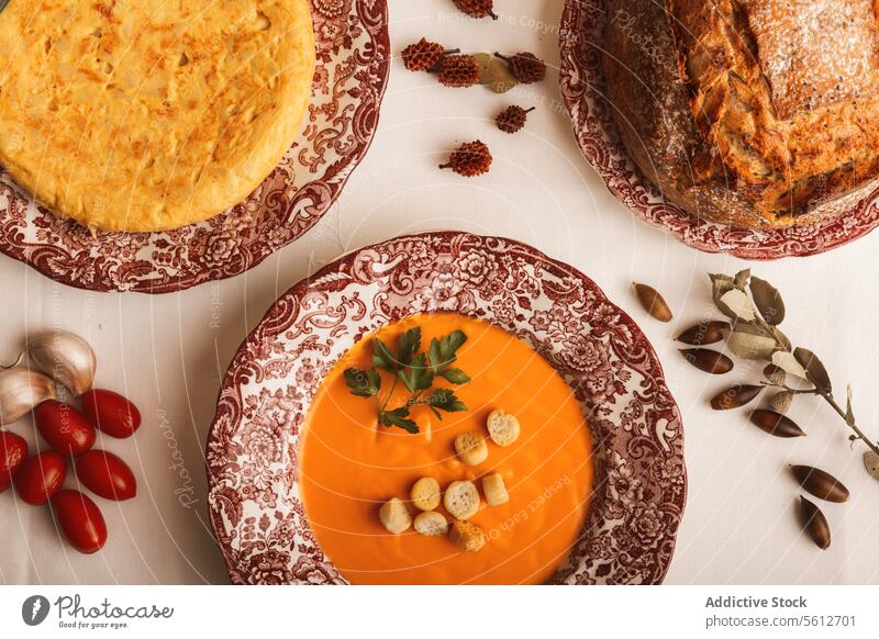 Leckeres spanisches Omelett und eine cremige Salmorejo-Suppe mit Croutons und Brot auf dekorativen Tellern. Herbst salmorejo Spanisch Kürbis Tisch gemütlich