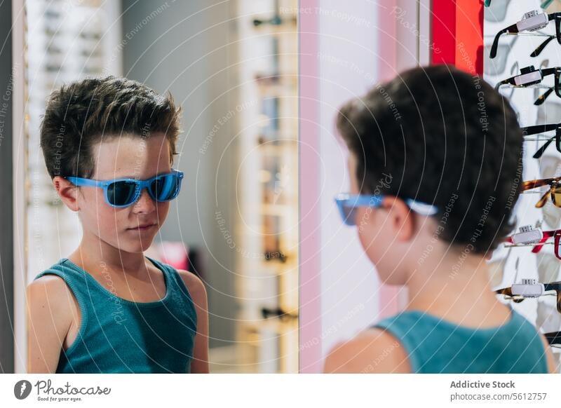 Kind probiert im Geschäft eine blaue Brille an Junge Sonnenbrille Spiegel niedlich stylisch anbindend kaufen optisch Laden Reflexion & Spiegelung Lifestyle