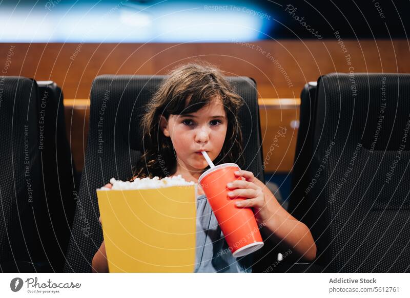 Mädchen mit Popcorn genießt einen Film im Kino Popkorn Eimer Theater niedlich geschmackvoll groß trinken Koks sitzen schwarz Sitz zuschauend Wochenende