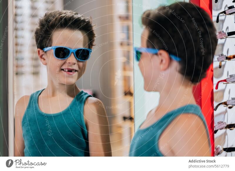 Kind probiert im Geschäft eine blaue Brille an Junge Sonnenbrille Lächeln Spiegel niedlich stylisch optisch Laden Reflexion & Spiegelung Lifestyle Gesicht