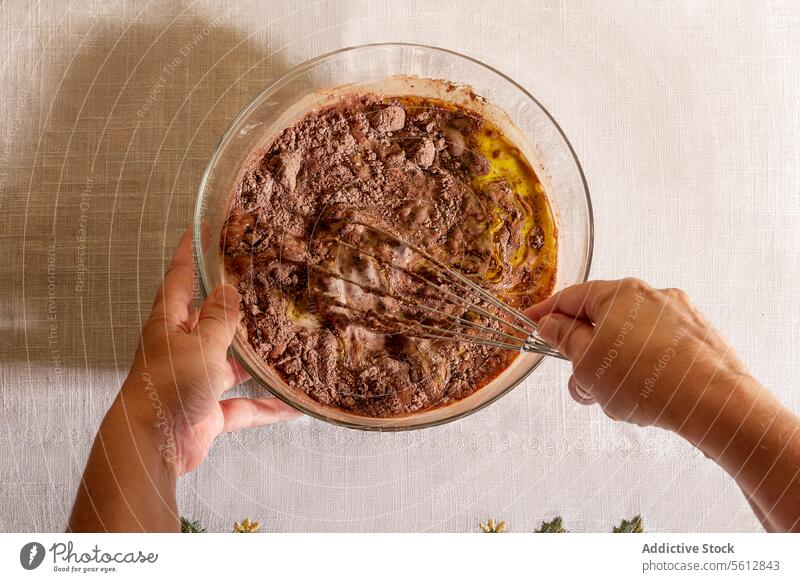 Draufsicht auf eine anonyme Person, die Schokoladenteig in einer Glasschüssel anrührt Küche Essen zubereiten backen Teig Schneebesen Mischen Hände