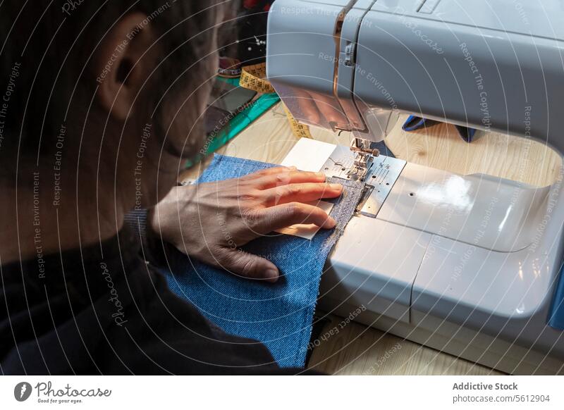 Denim auf einer Maschine mit geschickten Händen nähen Nähen Jeansstoff Hand Gewebe Handwerk Nadel Faser Textil Kleidungsstück Hobby Werkstatt Fähigkeit