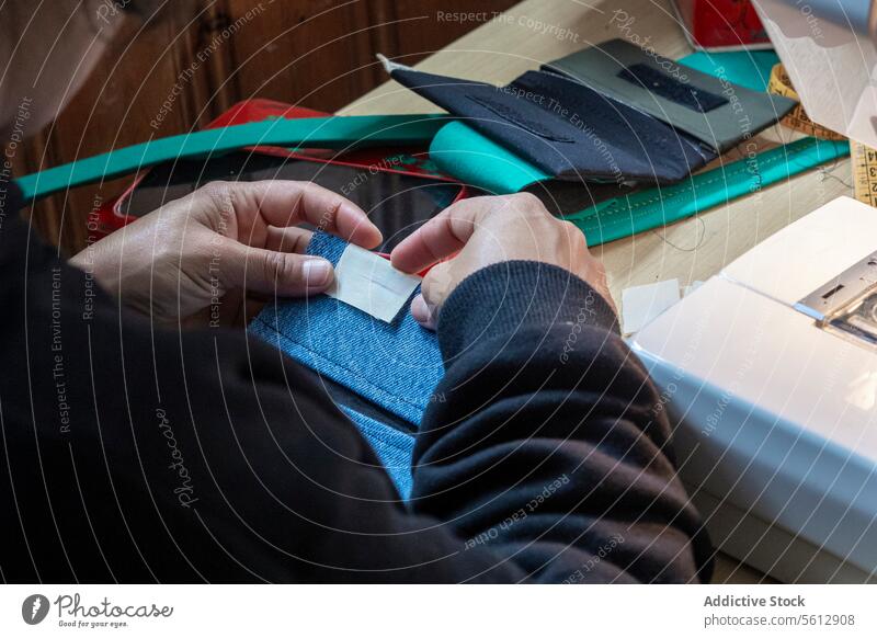 Schneiderin näht ein Kleidungsstück in ihrer Werkstatt Handnähen Gewebe Arbeitstisch Nahaufnahme penibel Handwerk Faser Nadel Nähmaschine Textil Mode