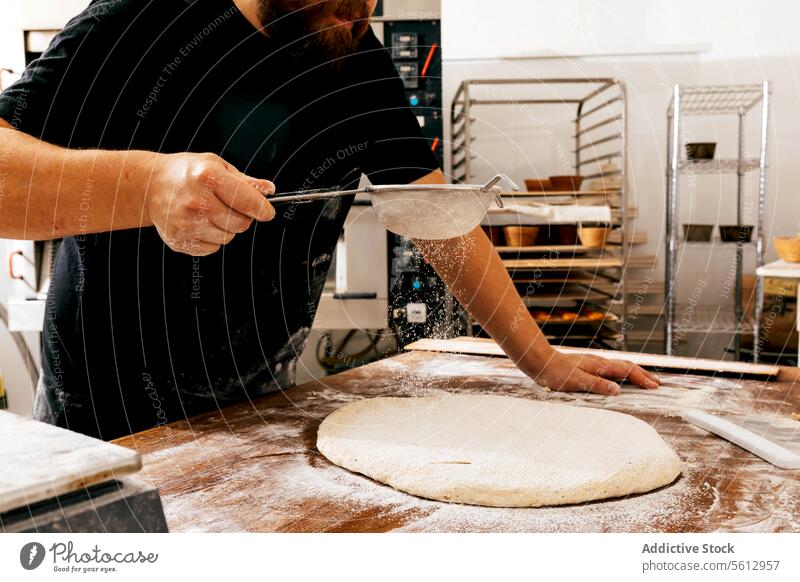 Erntehelfer siebt Mehl auf Teig am Tisch Küchenchef Sieben Teigwaren Bäcker hölzern Gebäck Herstellung Bäckerei bestäuben Brot Bestandteil kneten vorbereiten