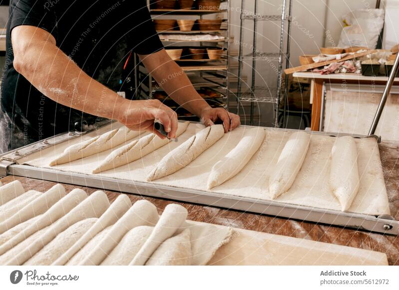 Anonymer Mann bereitet Brot in der Backstube zu Küchenchef Brotlaib punkten Schneiden Messer Tablett Hand Ernte Freizeitkleidung ungekocht backen Tisch