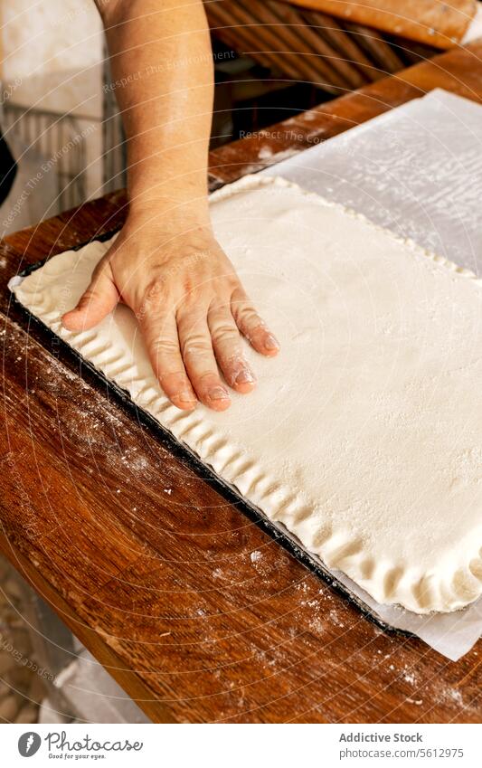 Die Hand des Kochs drückt die Teigkanten in der Küche Bäcker Teigwaren gefüllt Gebäck roh Ernte unkenntlich Herstellung Design Form Presse Saum Essen zubereiten