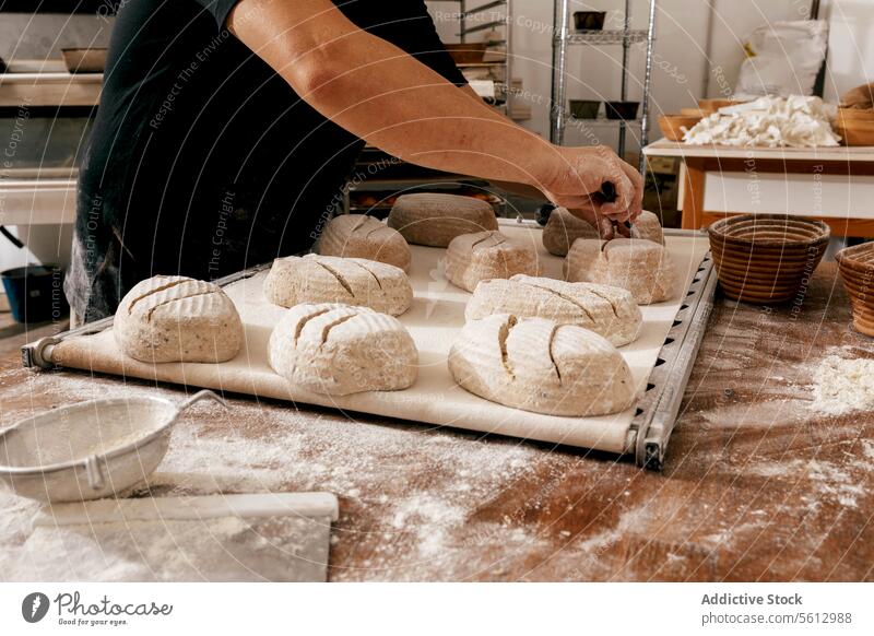 Bäcker schneidet Brotteig am Tisch in der Küche Küchenchef Teigwaren Messer Schneiden Hand Ernte unkenntlich ungekocht backen Tablett groß Bäckerei Körperteil