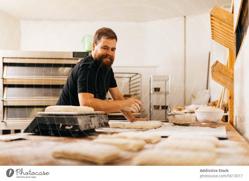 Koch bereitet Teig auf einem Tisch in einer Bäckerei vor Kneten Teigwaren Gebäck Küche Fokus Vollbart Freizeitkleidung Beruf Business Lebensmittel vorbereiten