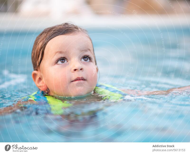 Nahaufnahme eines kleinen Jungen mit aufblasbarer Jacke im Schwimmbad, während er seinen Sommerurlaub genießt Schwimmsport Pool niedlich genießend Urlaub