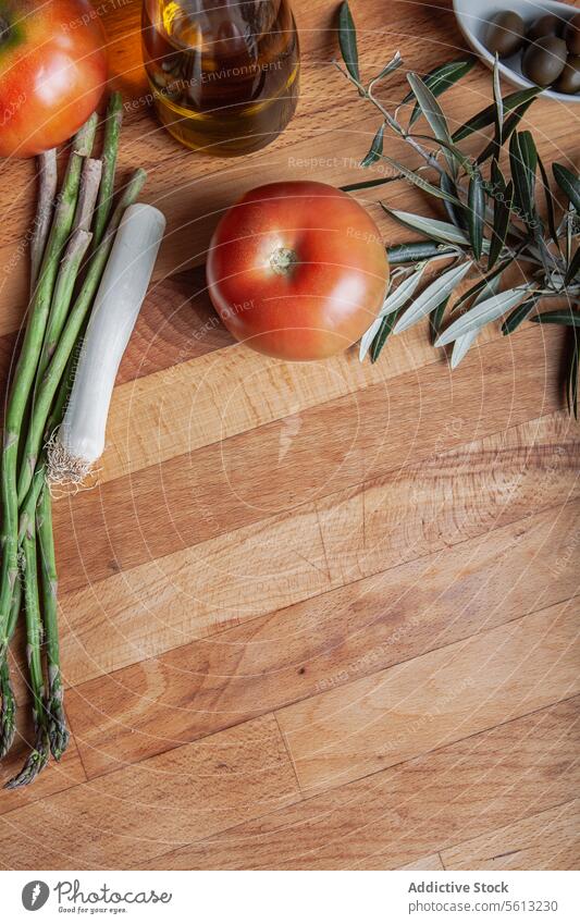 Frisches Gemüse und Olivenöl auf einem Holzbrett Tomate Spargel Porree oliv rustikal Schneidebrett Lebensmittel Bestandteil frisch reif kulinarisch Hintergrund