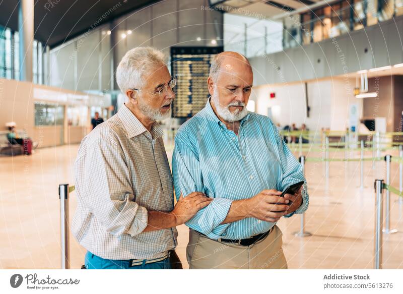 Ältere Reisende bei der Ticketkontrolle auf dem Flugplatz Passagier Freunde Männer prüfen Holzplatte Fahrkarte Zeitplanung warten Abheben Flughafen Vollbart