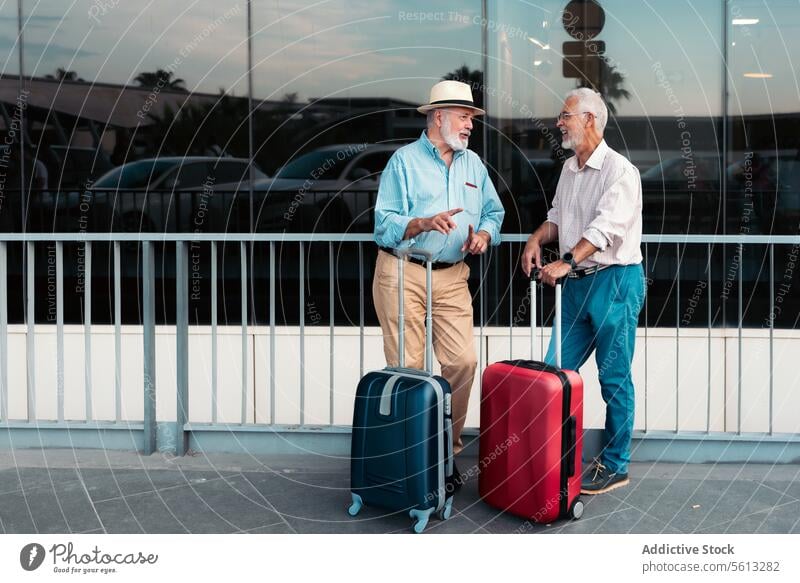 Ältere männliche Reisende warten vor dem Flughafen Freunde Senior Männer Koffer Fußweg Reling Valencia Ganzkörper Gepäck stehen Reisender Urlaub Zusammensein