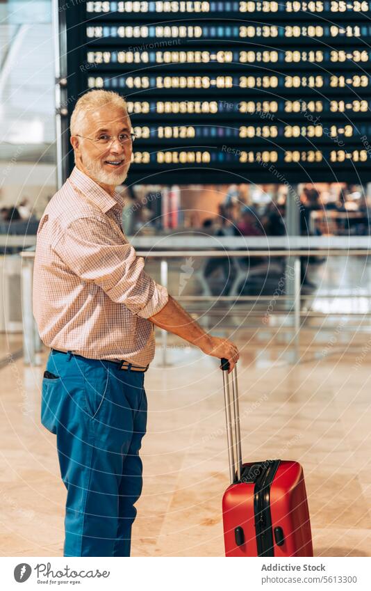 Mann mit Gepäck schaut in die Kamera am Flughafen Senior Abheben Holzplatte Lächeln Zeitplanung Seitenansicht Koffer Urlaub reisen in den Ruhestand getreten