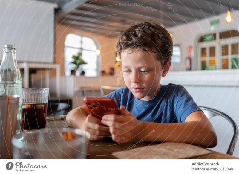Junge spielt mit Smartphone im Restaurant benutzend unschuldig Café speisend Tisch Sitzen Person Lifestyle Kind Kindheit Mobile Telefon Internet digital online