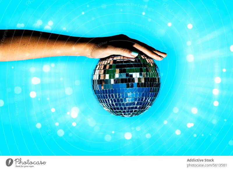 Frau hält Discokugel vor beleuchtetem Hintergrund Hand Beteiligung Ball hell Party Blendenfleck anonym Stilrichtung Club glänzend blau trendy gesichtslos