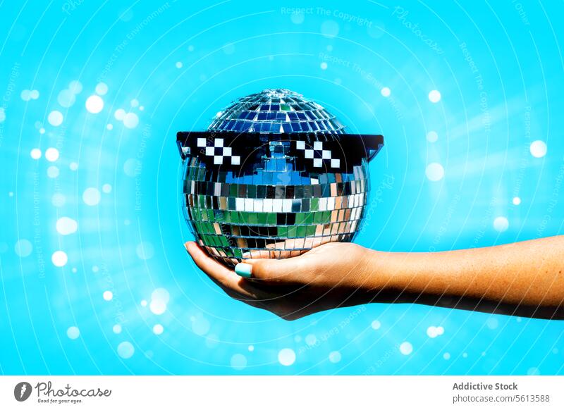 Frau mit Partybrille auf Discokugel vor blauem Hintergrund Hand Beteiligung Ball Brille beleuchtet hell glühen Blendenfleck anonym Stilrichtung Club glänzend