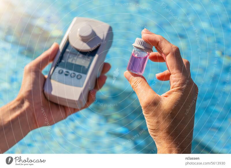 Person, die Schwimmbadwasser mit einem digitalen Testgerät und einem kleinen Probenbehälter untersucht digitales Prüfgerät ph-Prüfung chemisches Gleichgewicht