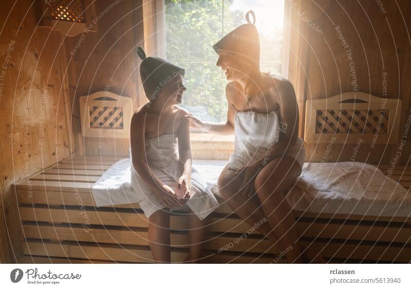 Mutter und Tochter genießen einen Saunagang, mit Filzhüten und in Handtücher gewickelt Bademantel Verdunstung Spa-Wellness Hotel Windstille Familie Frau Lächeln