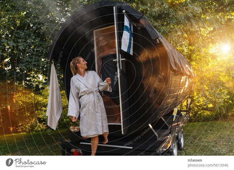 Menschen in Bademänteln stehen vor einem mobilen finnischen Saunafass mit Dampf um sie herum Nebel Mobile finnische Sauna Saunakabine Verdunstung Erholung