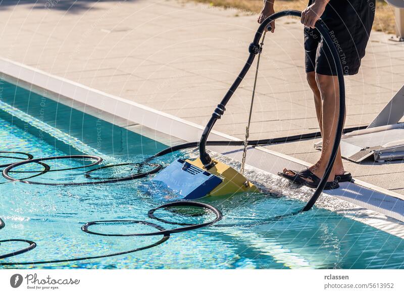 Person, die einen Bodensauger am Rande eines Schwimmbeckens bedient Frau Dienstleistungsbranche Technikeruniform Reinigungsroboter Poolpflege Sommer