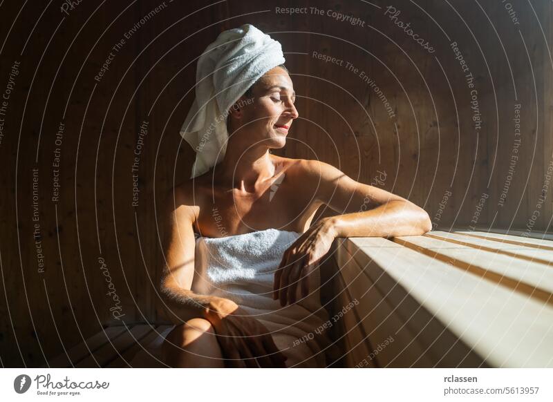 Ältere Frau sitzt entspannt in einer Holzsauna attraktiv Bad Bademantel schön Schönheit Schönheitssalon Körper Windstille Pflege Kaukasier bequem genießen