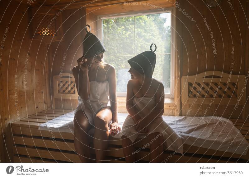Mutter und Tochter in einer Sauna, beide mit Filzhüten, unterhalten sich in einem Wellness-Hotel Bademantel Verdunstung Spa-Wellness Windstille Familie Frau