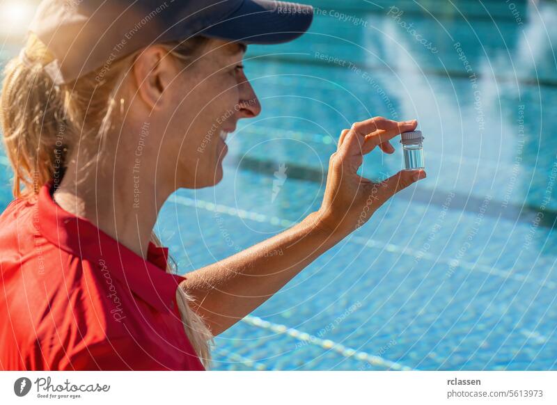 Ein lächelnder Schwimmbadtechniker hält ein kleines Fläschchen mit Schwimmbadwasser für einen pH-Test hoch. Tintenflüssigkeit gelbe Flüssigkeit Wert Chlor