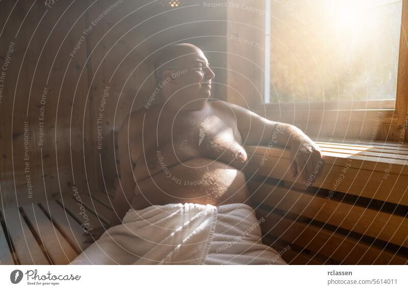 Zufriedener Mann, der sich in einer finnischen Sauna entspannt, während das Sonnenlicht durch das Fenster fällt. Wellnessbad Resort Hotel Schweiß Finnland