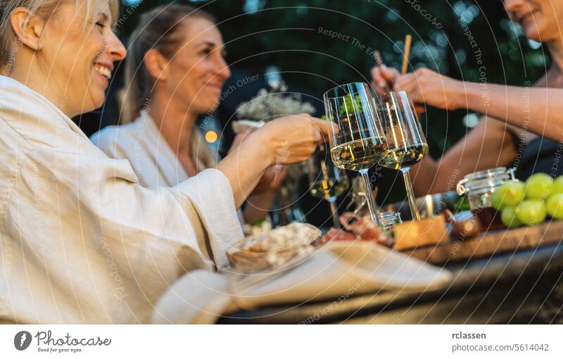 Freunde genießen in der Abenddämmerung Wein und Essen im Freien in der Nähe einer mobilen finnischen Sauna Lebensmittel finnische Sauna mobile Sauna Sammeln