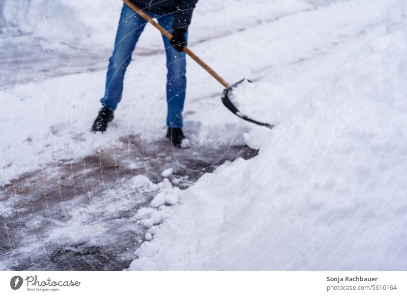 Ein Mann räumt einen Gehweg mit einer Schneeschaufel frei Winter schneeschieber Wintertag Wintereinbruch Teilansicht Dezember Winterstimmung Wetter winterlich