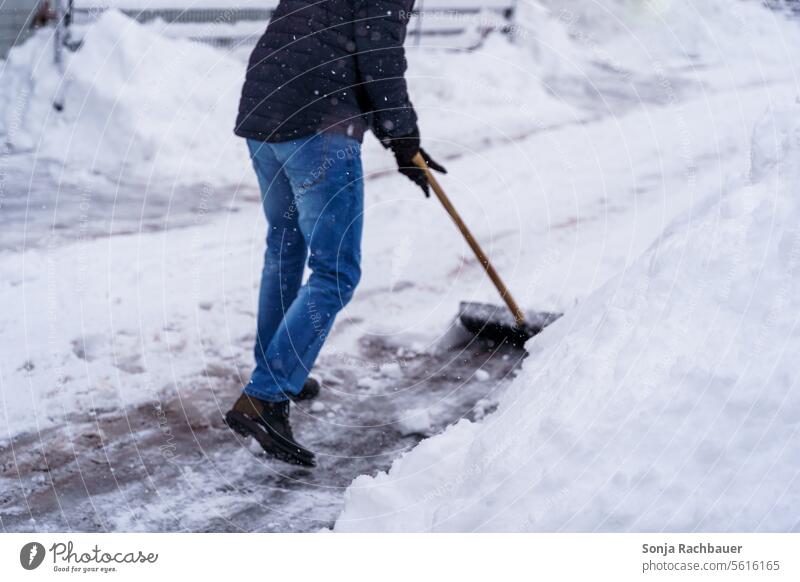 Ein Mann räumt mit einer Schneeschaufel eine Strasse frei Winter Winterdienst Schneefall Straße Wege & Pfade Schneedecke Wintertag Tag Kälte frieren Umwelt