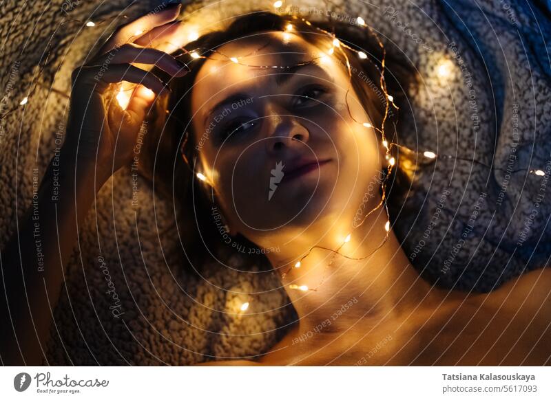 Nahaufnahme des Gesichts einer Frau mit Lichterketten Schnur beleuchtet verwickelt Nacht dunkel liegend Kopf Abend elektrisch Kurze Haare Zärtlichkeit