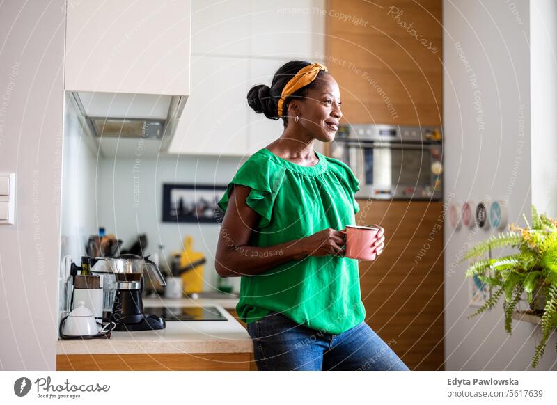 Porträt einer lächelnden reifen Frau, die in ihrer Küche steht und Kaffee trinkt Menschen Freude schwarz natürlich attraktiv schwarze Frau Fröhlichkeit Glück