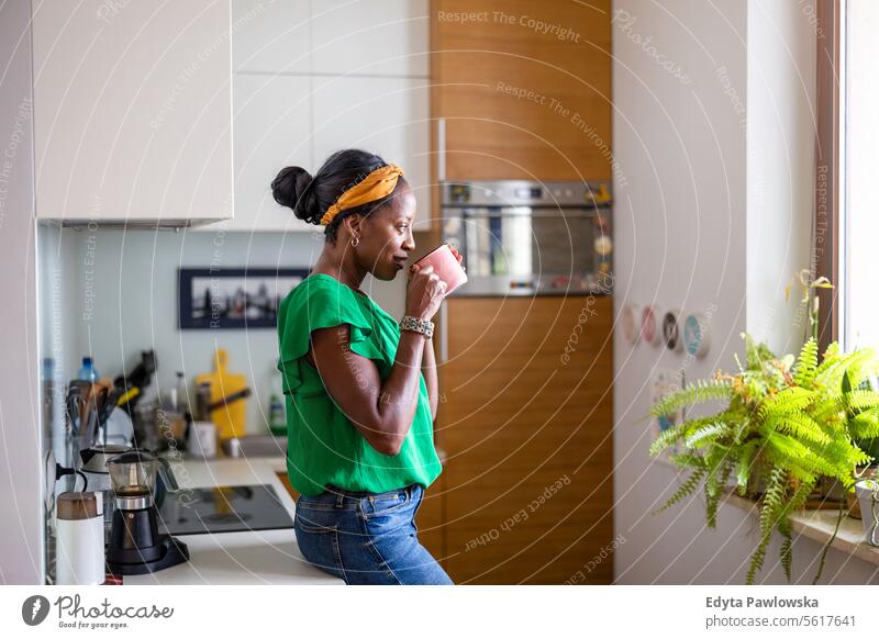 Porträt einer lächelnden reifen Frau, die in ihrer Küche steht und Kaffee trinkt Menschen Freude schwarz natürlich attraktiv schwarze Frau Fröhlichkeit Glück