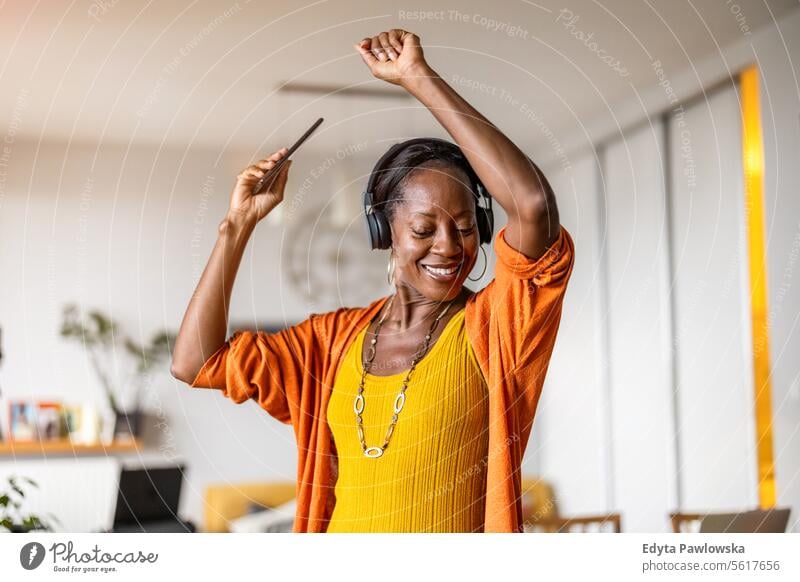Frau hört Musik mit Kopfhörern im heimischen Wohnzimmer Menschen Freude schwarz natürlich attraktiv schwarze Frau Fröhlichkeit Glück echte Menschen reif