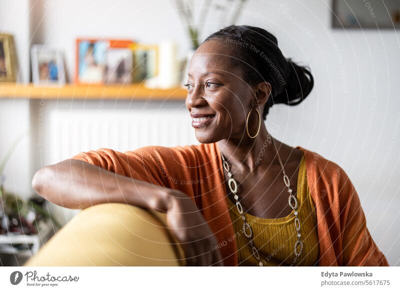 Porträt einer lächelnden Frau, die sich zu Hause auf dem Sofa entspannt Menschen Freude schwarz natürlich attraktiv schwarze Frau Fröhlichkeit Glück
