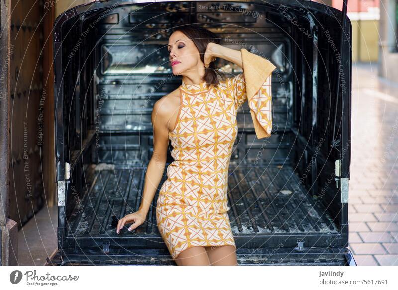 Verführerische Frau in stilvollem Kleid sitzt am Eingang eines Wohnwagens sinnlich Make-up Model romantisch Verlockung Straße Stil Kleintransporter