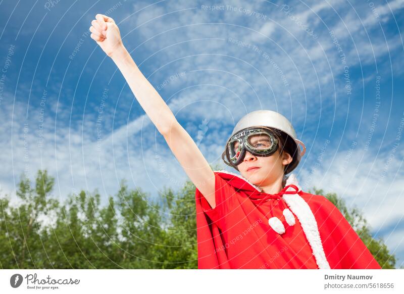 Low-Winkel-Ansicht von niedlichen Teenager-Junge trägt Metall Kessel als Helm Schutzbrille und roten Kostüm - eine lustige Macht Superheld Kind Konzept