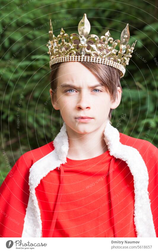 Porträt eines Teenagers mit Krone und rotem Umhang, der vorgibt, ein König zu sein Gesichtsausdruck Jugendlicher Hochmut Autorität Junge Kap Karneval Kind