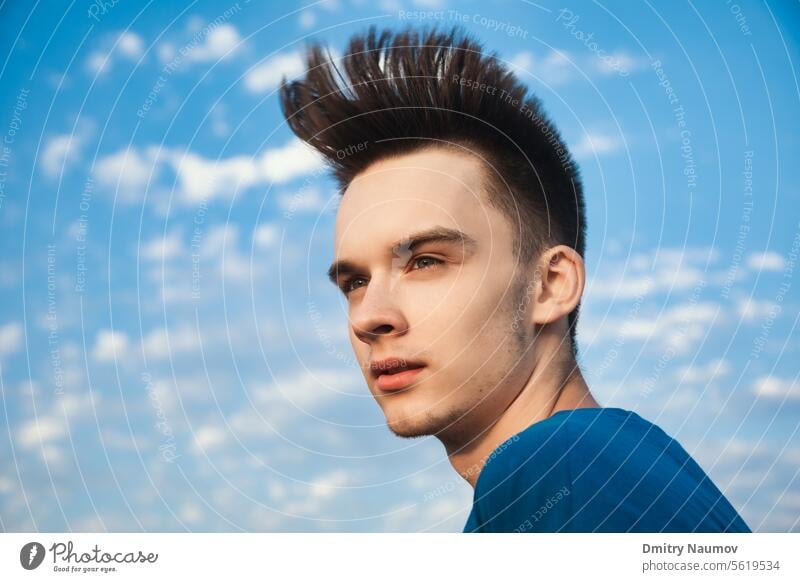 Porträt eines Teenagers im Freien, der wegschaut und dessen Haare im Wind gegen den Abendhimmel wehen Generation z allein attraktiv blasend Junge Windstille
