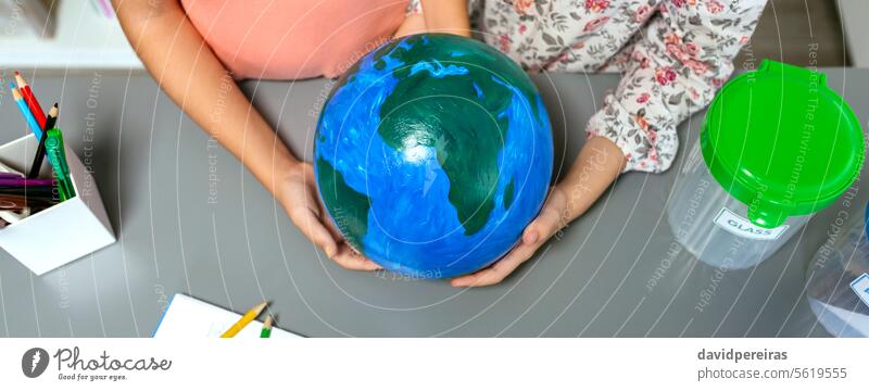 Zwei unkenntliche Studentinnen halten einen handgefertigten Globus der Erde Frau Schüler Beteiligung Welt Planet Hand wenig Mädchen Schule Transparente Panorama
