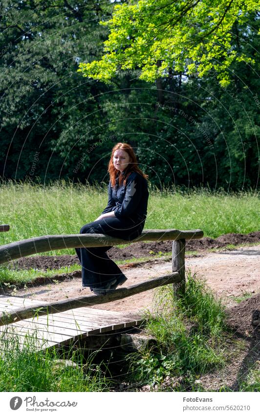 Eine junge Frau sitzt auf dem Geländer einer Brücke in der Natur Frauen Teenager deprimiert Rotschopf backgrund Tag Depression Sommer Mädchen außerhalb allein