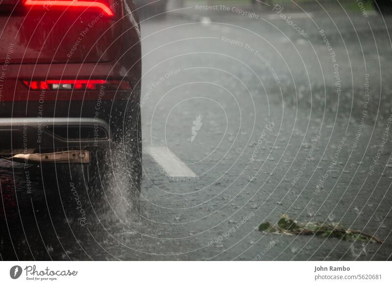 Regenwasser Spritzwasser fließen von den Rädern des roten Auto schnell in Tageslicht Stadt mit selektivem Fokus bewegen. PKW bewegend Asphalt Straße während